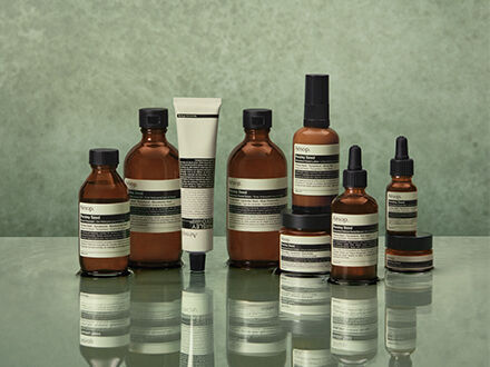 Aesop skincare products on a reflective surface.