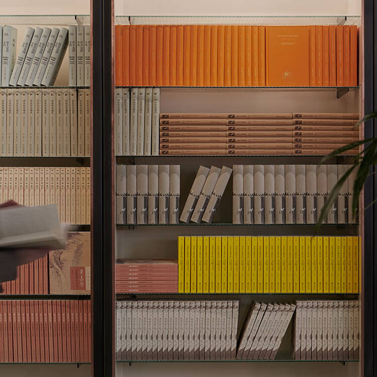 Warm wooden shelves filled with yellow, orange, and red books.